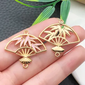 Macro view of gold and pink enamel bamboo leaf fan charms for DIY jewelry crafting