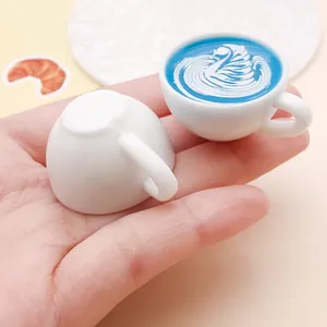 Detailed view of miniature resin coffee cups featuring blue swan latte art patterns for DIY craft
