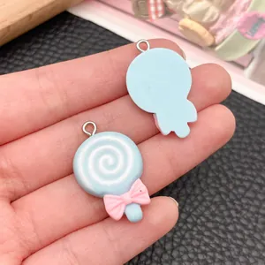 Close-up of blue resin lollipop charms with pink bows for DIY jewelry and crafts