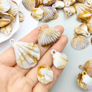 Detailed view of acrylic scallop shell charms with natural marbling held in hand for size
