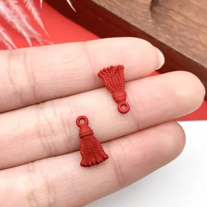 Vista detallada de pequeños colgantes de borla rojos en la punta del dedo para joyas DIY
