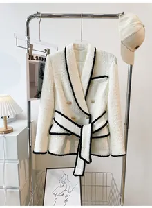 Elegant white tweed blazer with black trim and gold buttons displayed on a rack