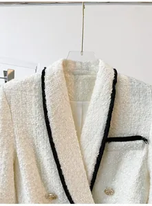Detailed close-up of white tweed jacket with black trim details and gold buttons