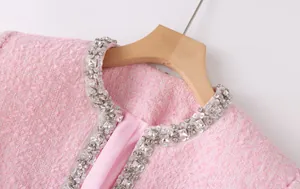 Detailed view of the sparkling rhinestone and sequin collar on a pink tweed jacket.