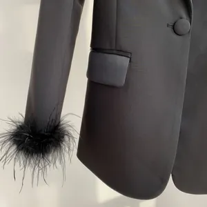 Macro view of black blazer sleeve with ostrich feather trim and pocket flap detail