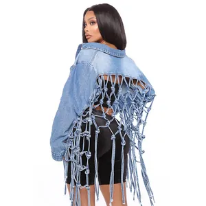 Détail d'une veste en jean pour femme avec un design complexe de franges en maille.