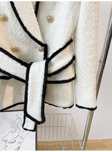 Detailed view of luxury white tweed jacket with gold lion buttons and black fringe trim