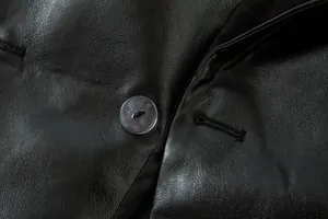 Detalle macro de chaqueta de cuero sintético negro con textura fina y botón de resina