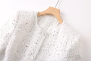 Gros plan sur la texture du tweed blanc tissé et les boutons décoratifs scintillants