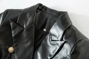 Detalle de una blazer de cuero sintético negro con botón de cabeza de león dorado