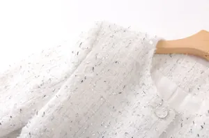 Détail d'une veste en tweed blanc avec fils métalliques argentés et texture tissée