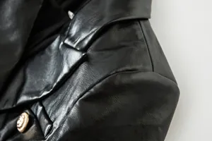 Detalle macro de la solapa de una chaqueta de cuero sintético negro con botón dorado