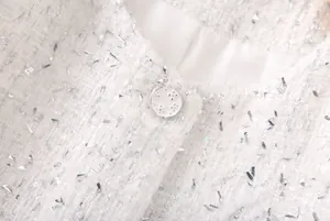 Détail macro du tissu en tweed tressé blanc et bouton décoratif sur une veste de luxe