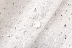 Détail macro du tissu en tweed blanc avec paillettes argentées et bouton rond décoratif