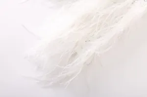Détail en gros plan des plumes d'autruche blanches sur une veste en tweed élégante