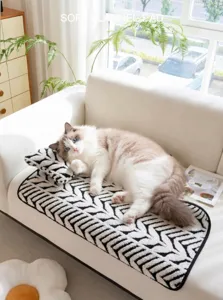 Tappetino per animali in peluche con motivo geometrico e cuscino su divano bianco