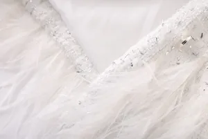 Détail de tissu en tweed blanc avec paillettes scintillantes et plumes délicates