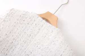 Gros plan sur le tissu en tweed blanc avec des paillettes argentées scintillantes.
