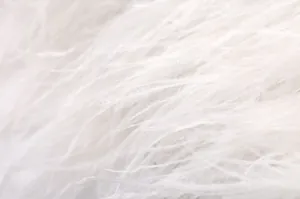 Macro-détail de la bordure en plumes blanches pour cette veste en tweed français