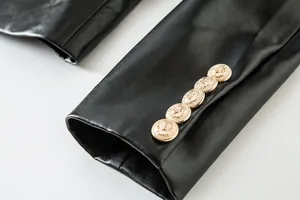 Detalle de la manga de chaqueta de cuero sintético negro con botones de león dorados