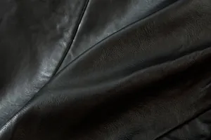Primer plano detallado de la textura de cuero sintético negro con acabado de grano natural.