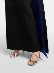 Elegante vestido largo con paneles en negro y azul y sandalias plateadas metálicas.