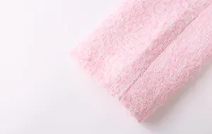 Macro view showing the detailed texture of pink and white woven tweed fabric for women's suits.