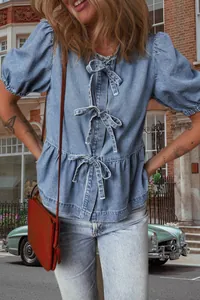 Dettaglio di un'elegante camicetta di jeans con chiusure a fiocco multiple sul davanti