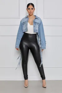 Détail d'une veste en jean courte bleu clair avec des pompons à franges au dos