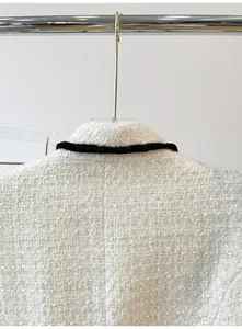 Detailed macro view of white tweed blazer collar featuring contrast black trim texture