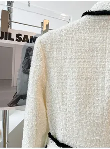 Close-up of high-quality white tweed fabric texture with black fringe detail