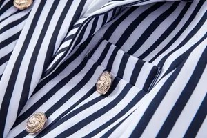 Detalle de los botones dorados con cabeza de león en una elegante chaqueta de rayas.