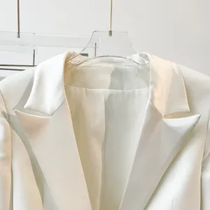 Detailed macro view of an elegant snow white blazer featuring sharp notched lapels and satin finish