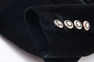 Close-up detail of black velvet blazer cuff with decorative gold buttons.