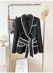 Detailed shot of an elegant black tweed blazer featuring white fringe trim and gold buttons