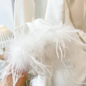 Close-up showing the delicate texture of fluffy white ostrich feather trim on a sleeve