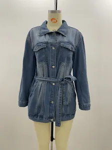 Detailopname van een blauw halflang spijkerjack met knoopsluiting en bijpassende tailleriem.