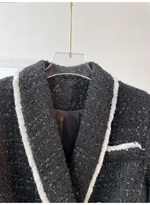 Close-up detail of a premium black tweed jacket with white frayed trim and texture.