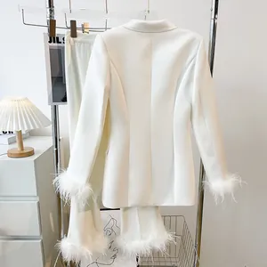 Detailed view of white blazer with elegant feather-trimmed cuffs and hem