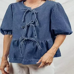 Vista dettagliata della camicetta in denim blu con fiocchi e maniche a sbuffo