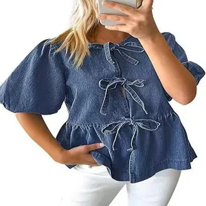 Dettaglio di camicia in denim con maniche a sbuffo, fiocchi frontali e fondo a peplo