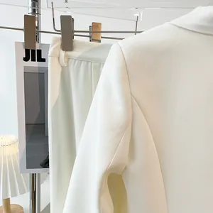 Close-up detail showing the texture of a minimalist snow white blazer and trousers suit