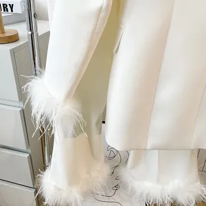 Close-up detail of snow white minimalist blazer and trousers set with feather trim.