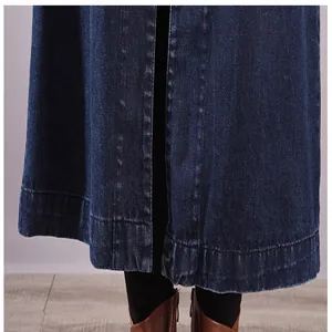 Close-up view of the long denim dress hem featuring a central slit design