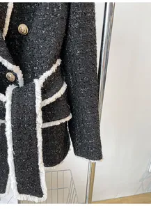 Detailed macro shot of black tweed jacket featuring frayed edges and lion head buttons