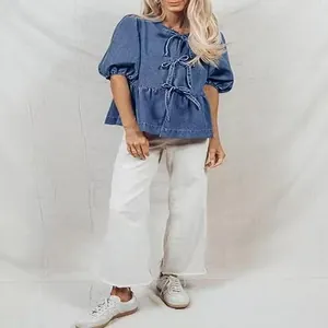 Vista a figura intera di una camicia in denim con fiocchi, maniche a sbuffo e volant