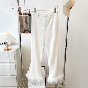 Detail view of elegant snow white leisure trousers with chic faux feather hem trim