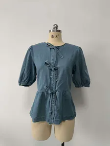 Dettaglio della camicetta in denim blu con eleganti fiocchi sul davanti
