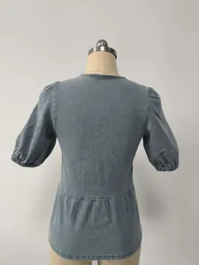 Vista posteriore dettagliata di una camicia in denim blu sbiadito con maniche a sbuffo