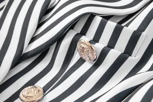 Primer plano de botones dorados con cabeza de león en un blazer a rayas.